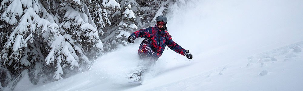 Snowboarder carving through deep powder in Idaho, showcasing the thrill of snowboarding on pristine trails at top ski resorts, a perfect destination for winter tourism and adventure.